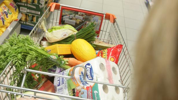 Ein Einkaufswagen gefüllt mit Lebensmitteln wie Gemüse, Obst und Toilettenpapier.