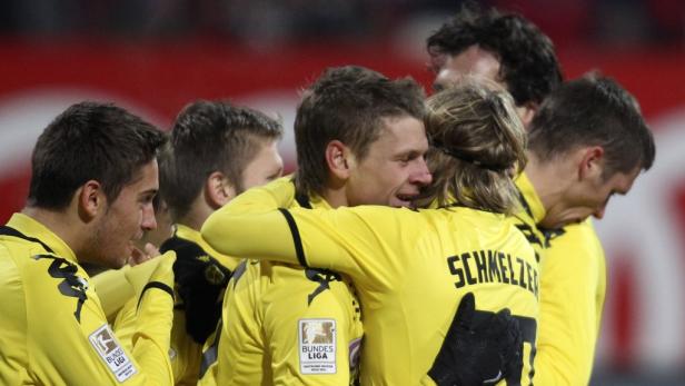 Fußballspieler von Borussia Dortmund umarmen sich in gelben Trikots.