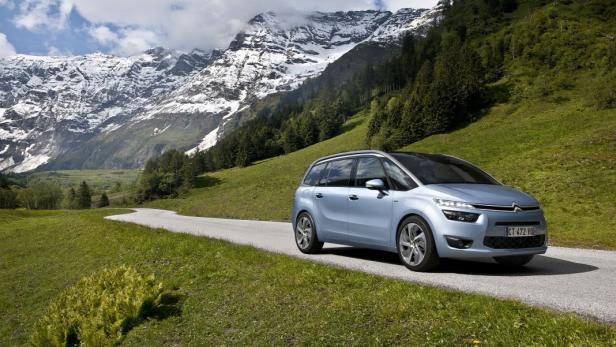 Ein blauer Citroën steht auf einer Straße vor einer Berglandschaft.