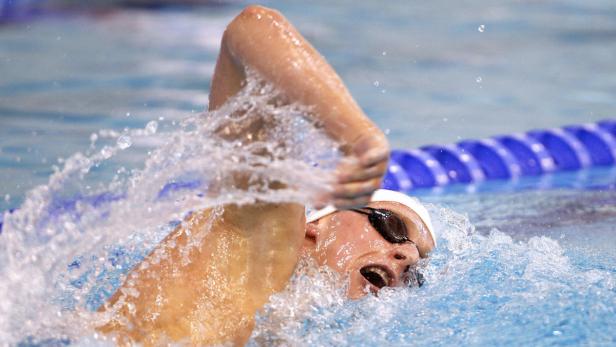 Eine Schwimmerin mit Schwimmbrille beim Kraulen in einem Schwimmbecken.