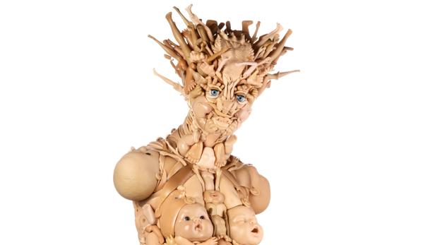 Eine bizarre Skulptur, geformt aus Puppenteilen, mit einem Gesicht und einem Oberkörper.