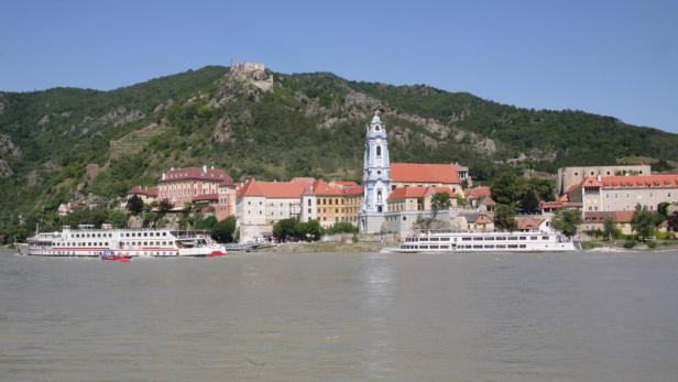 Blick auf Dürnstein in der Wachau mit der Stiftskirche und zwei Ausflugsschiffen auf der Donau.