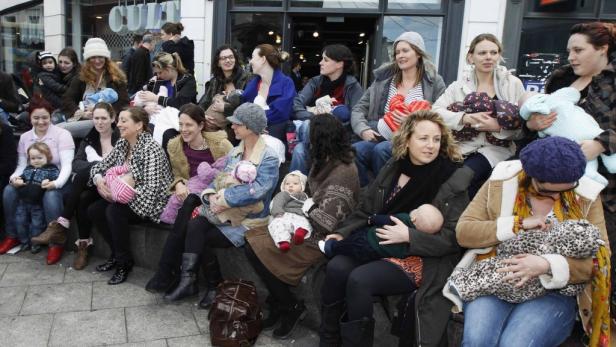 Eine Gruppe von Müttern sitzt draußen und stillt ihre Babys.