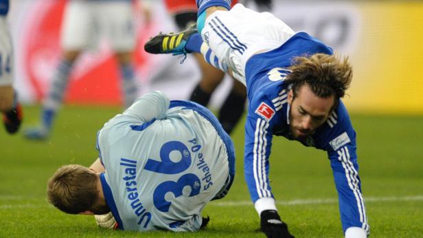 Ein Fußballspieler stürzt über einen am Boden liegenden Torwart.