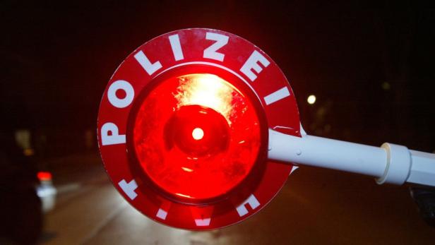 Ein rot leuchtender Verkehrskegel der Polizei bei Nacht.