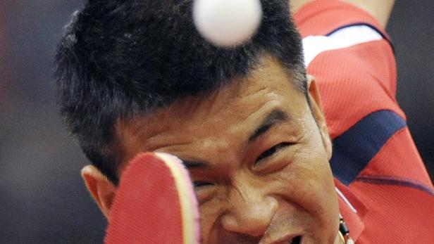 Ein Tischtennisspieler schlägt einen Ball mit seinem Schläger.