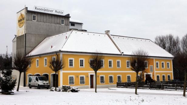 Die Rosenfellner Mühle im Winter mit Schnee auf dem Dach.