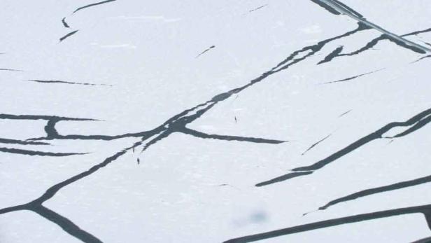 Risse in einer hellen, möglicherweise eisigen Oberfläche.