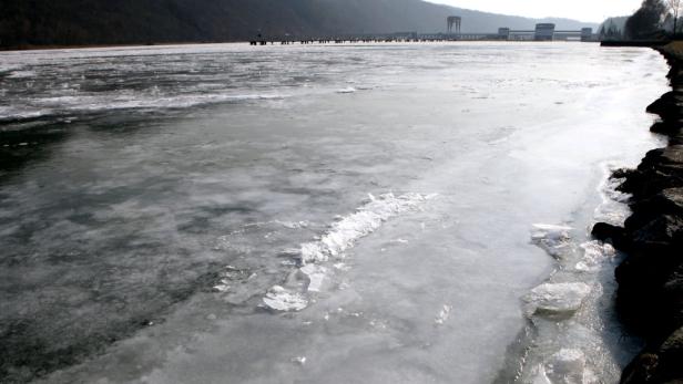 Eine zugefrorene Wasserfläche mit einem Gebäude im Hintergrund.