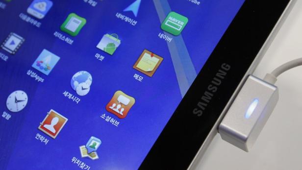 Ein Samsung Tablet wird über einen Adapter aufgeladen; der Bildschirm zeigt koreanische Apps.