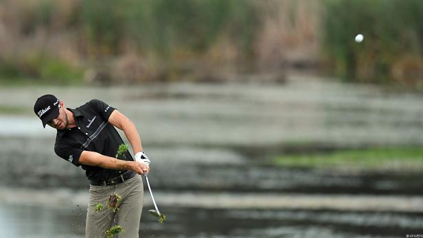 Ein Golfspieler schlägt einen Ball über eine Wasserhindernis.