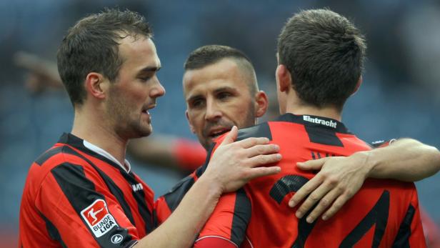 Drei Fußballspieler von Eintracht Frankfurt umarmen sich.