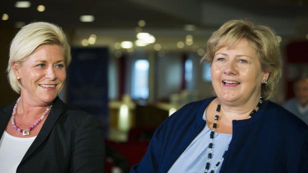 Zwei blonde Frauen stehen lächelnd nebeneinander.