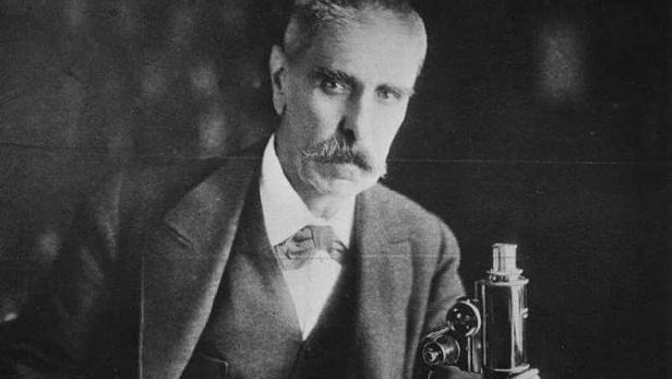 Ein Porträt von Santiago Ramón y Cajal mit einem Mikroskop.