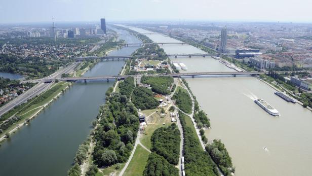 Luftaufnahme der Donauinsel in Wien mit mehreren Brücken und der Skyline im Hintergrund.