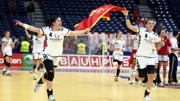 Zwei Handballspielerinnen feiern mit der montenegrinischen Flagge einen Sieg.