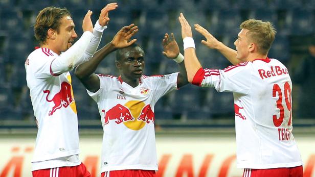 Drei Fußballspieler von Red Bull jubeln gemeinsam auf dem Spielfeld.