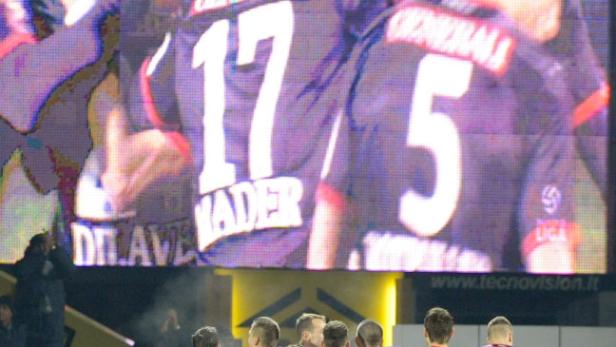 Eine Gruppe Fußballspieler in lila Trikots umarmt sich auf dem Spielfeld.
