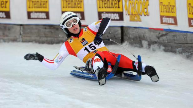 Eine Rennrodlerin auf einer Eisbahn während eines Wettkampfs.