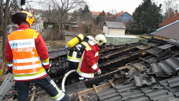 Feuerwehrleute arbeiten auf einem beschädigten Dach nach einem Brand.