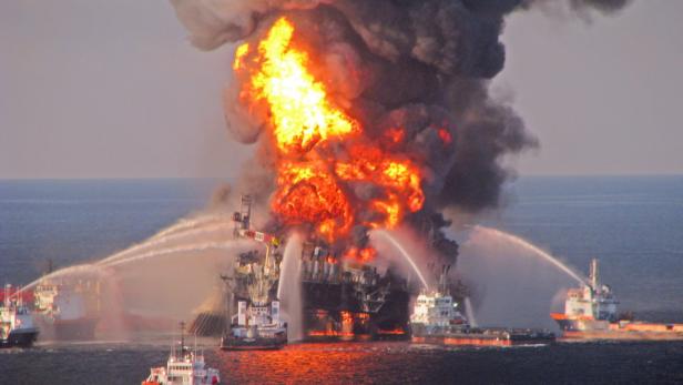 Eine Ölplattform steht in Flammen, während Löschboote Wasserwerfer einsetzen.