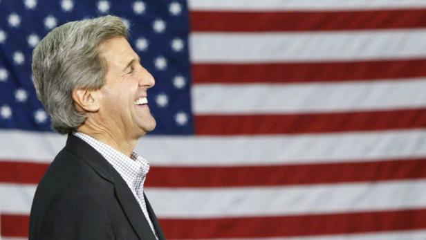 John Kerry lächelt vor einer amerikanischen Flagge.