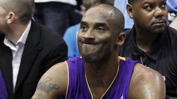 Kobe Bryant in einem lila Trikot sitzt auf der Bank.