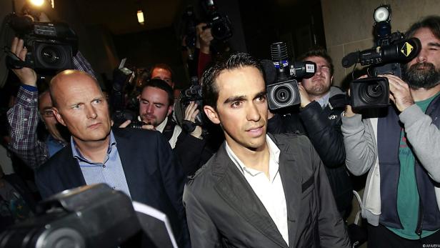 Zwei Männer werden von einer Gruppe von Fotografen umringt.