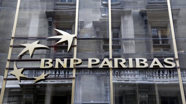Die goldene Fassade der BNP Paribas Bank mit Sternenlogo spiegelt ein Gebäude wider.
