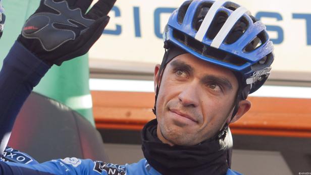 Ein Radrennfahrer mit blauem Helm blickt zur Seite und winkt.