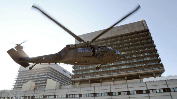 Ein Militärhubschrauber fliegt vor einem hohen Gebäude.