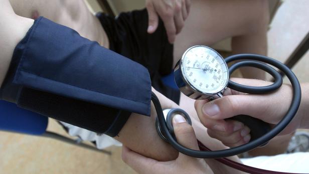 Ein Arzt misst den Blutdruck eines Patienten mit einem Blutdruckmessgerät.