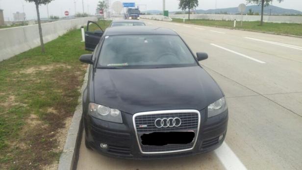 Ein schwarzer Audi A3 steht mit geöffneter Tür am Straßenrand.