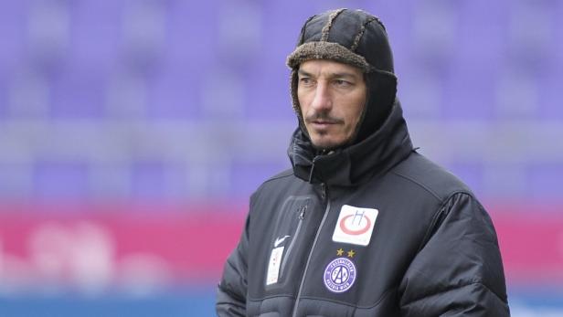 Ein Mann mit Mütze und Winterjacke vor einem violetten Hintergrund.