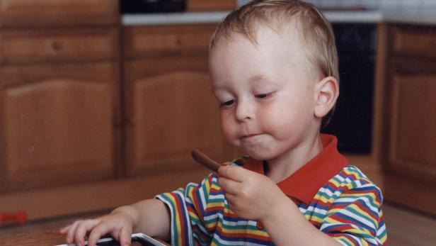 Ein kleiner Junge isst einen Schokoriegel.