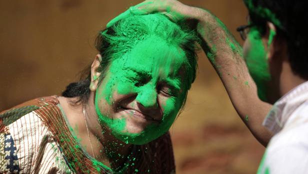 Eine Frau wird mit grüner Farbe während des Holi-Fests bemalt.