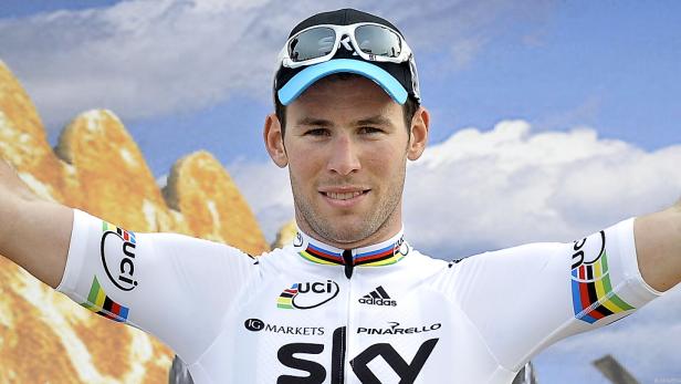 Ein Radrennfahrer im weißen Trikot mit Sponsorenlogos lächelt.