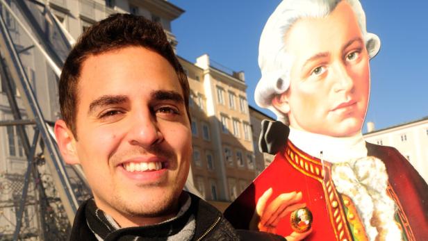 Ein lächelnder Mann posiert mit einem Pappaufsteller von Mozart in Salzburg.