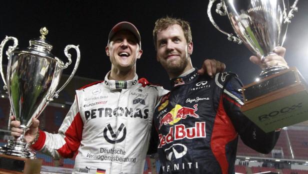 Michael Schumacher und Sebastian Vettel halten Trophäen in die Höhe.