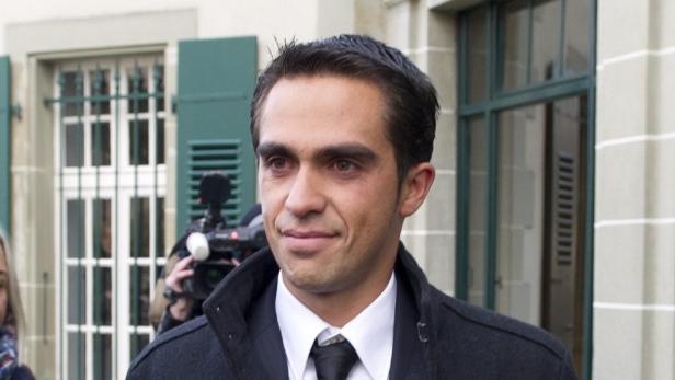 Ein Mann in Anzug und Mantel steht vor einem Gebäude.