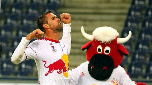 Ein Fußballspieler jubelt neben dem Maskottchen von Red Bull Salzburg.