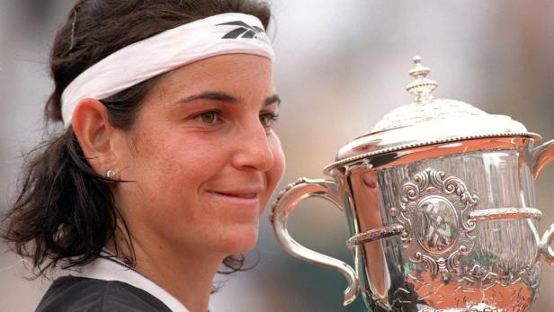 Eine Tennisspielerin lächelt mit der Trophäe der French Open im Arm.