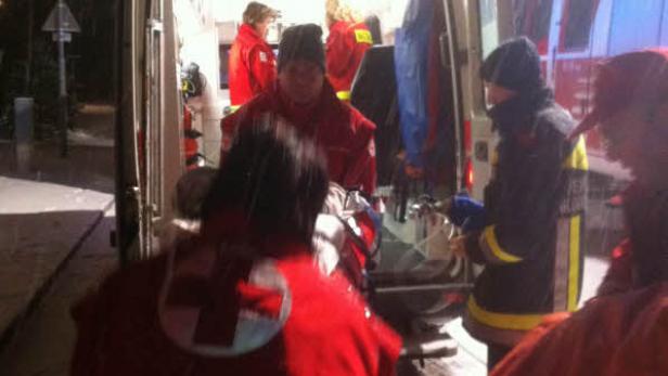 Rettungskräfte laden eine Person in einen Krankenwagen bei Schneefall.