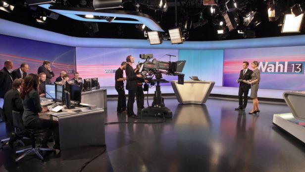 Ein Fernsehstudio mit Moderatoren, Kameraleuten und Technikern bei der Arbeit.