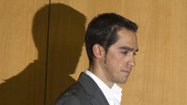 Ein Mann im Anzug, im Profil vor einer Holzwand, mit seinem Schatten.