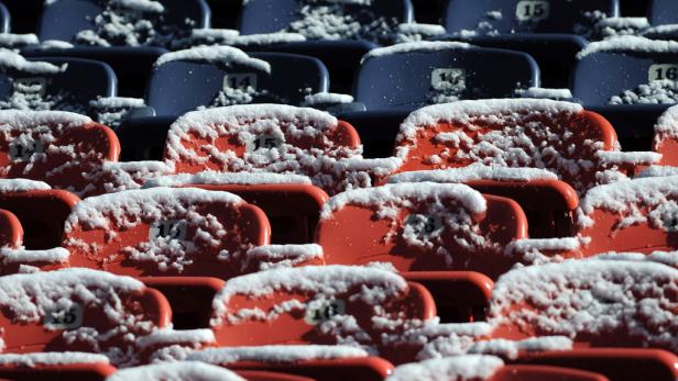 Schnee bedeckt die nummerierten Sitze in einem Stadion.