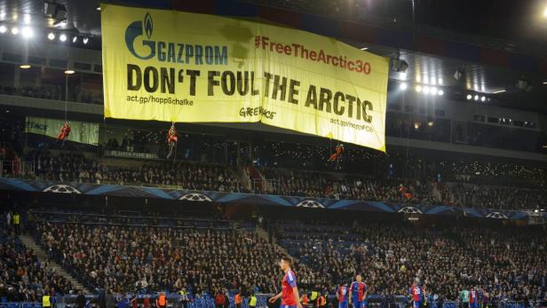 Aktivisten seilen sich in einem Fußballstadion von einem Banner mit der Aufschrift „Don't Foul the Arctic“ ab.