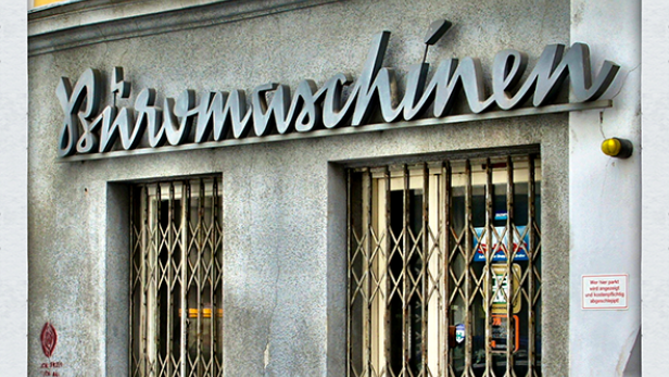 Ein Geschäft mit dem Schriftzug „Büromaschinen“ über den vergitterten Fenstern.