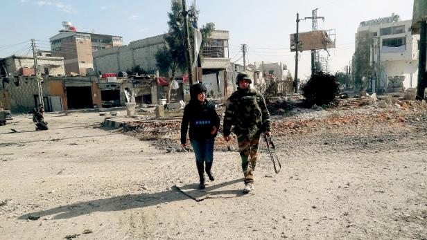 epa03494546 A handout picture released by Syrian Arab News Agency (SANA) shows a journalist walking with a Syrian army soldier during a patrol in Darayah area, southern rural Damascus, Syria, 02 December 2012. Syrian government troops Sunday intensified attacks on pro-rebel suburban areas of the capital, Damascus, reported opposition activists. EPA/SANA HANDOUT EDITORIAL USE ONLY/NO SALES