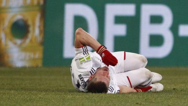 Ein Fußballspieler liegt mit schmerzverzerrtem Gesicht auf dem Rasen.